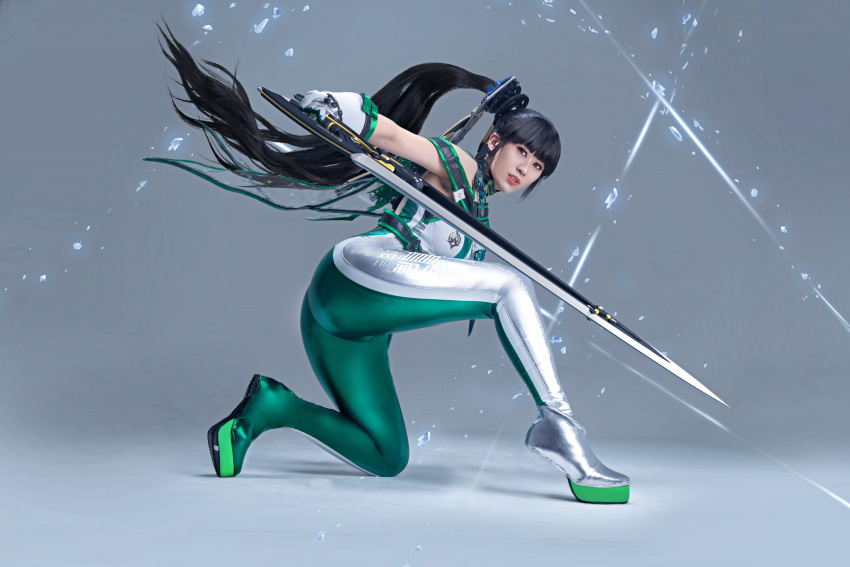 1girl ass black_eyes black_hair bodysuit cosplay_photo english_commentary eve_(stellar_blade) floating from_behind gloves green_bodysuit green_footwear grey_background grey_bodysuit grey_footwear highres larissa_rochefort long_hair looking_at_viewer on_one_knee parted_lips photo_(medium) ponytail shadow sleeveless sleeveless_bodysuit solo stellar_blade two-tone_bodysuit very_long_hair white_gloves