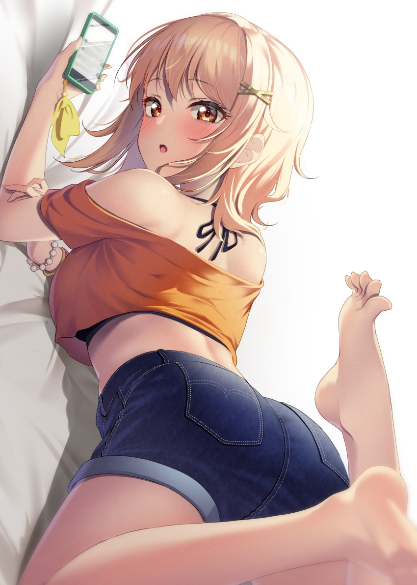 1girl :o absurdres ass barefoot bead_bracelet beads bed_sheet blonde_hair blurry blush bracelet breasts cellphone cellphone_charm charm_(object) crop_top denim denim_shorts depth_of_field feet feet_up hair_ornament hairclip halterneck highres holding holding_phone jewelry legs looking_at_viewer looking_back love_live! love_live!_nijigasaki_high_school_idol_club lying miyashita_ai off-shoulder_shirt off_shoulder oku_1225 on_stomach open_mouth orange_eyes orange_shirt phone pillow shirt shorts smartphone solo spread_toes toes wristband x_hair_ornament