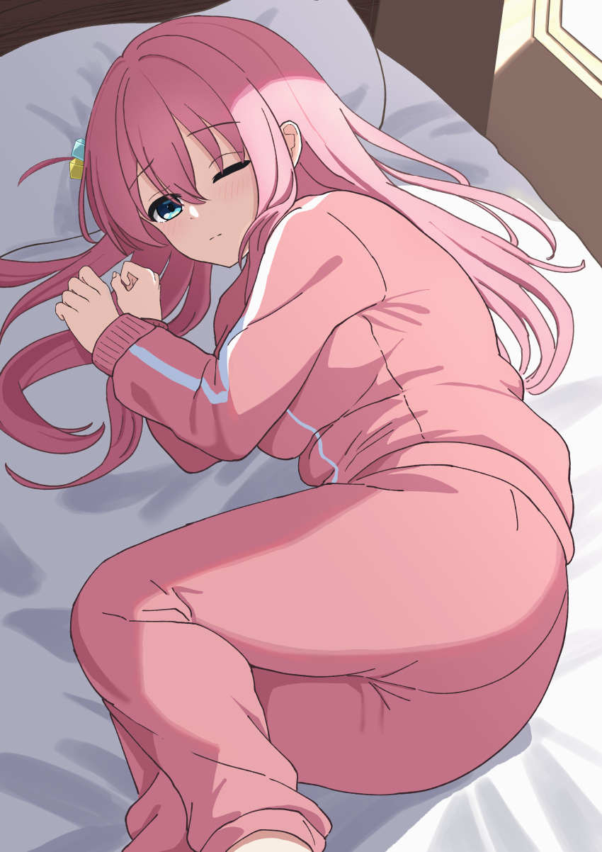 1girl absurdres bangs bed blue_eyes bocchi_the_rock! cube_hair_ornament gotou_hitori hair_between_eyes hair_ornament highres indoors jacket long_hair looking_at_viewer lying on_bed on_side one_eye_closed one_side_up pants pink_hair pink_jacket pink_pants pink_track_suit pogeepoge solo track_jacket