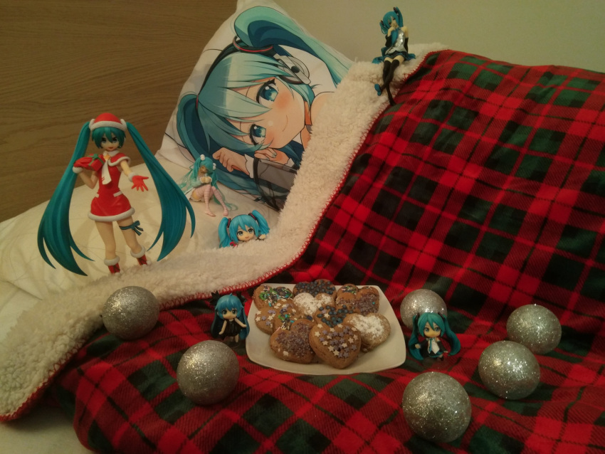 1girl 2d_dating bauble blue_hair cookie dakimakura_(object) figure food gift hat hatsune_miku heart highres long_hair non-web_source photo_(medium) pillow plaid plate santa_costume santa_hat solo twintails under_covers very_long_hair vocaloid