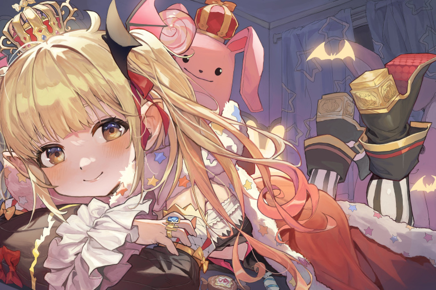 1girl absurdres bat_(animal) bat_hair_ornament blonde_hair blush boots brown_eyes candy cape chamchamshia crown curtains food frilled_sleeves frills futaba_anzu hair_ornament high_heel_boots high_heels highres idolmaster idolmaster_cinderella_girls indoors jewelry long_hair looking_at_viewer lying on_stomach pointy_ears ring smile solo stuffed_animal stuffed_rabbit stuffed_toy wide_sleeves