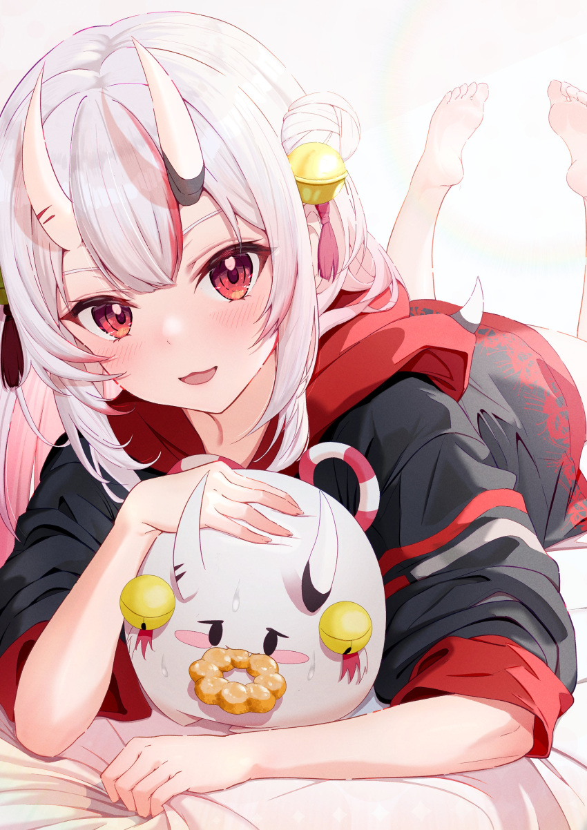 1girl absurdres bed bell black_hoodie blush colored_inner_hair commentary_request doughnut feet feet_up food full_body gradient_hair grey_background grey_hair hair_bell hair_bun hair_ornament highres hihi_(oekakihix) hololive hood hood_down hoodie horns looking_at_viewer lying multicolored_hair nakiri_ayame on_stomach oni_horns open_mouth parted_bangs pink_hair poyoyo_(nakiri_ayame) red_eyes red_hair sidelocks simple_background single_side_bun skin-covered_horns soles solo streaked_hair toes virtual_youtuber