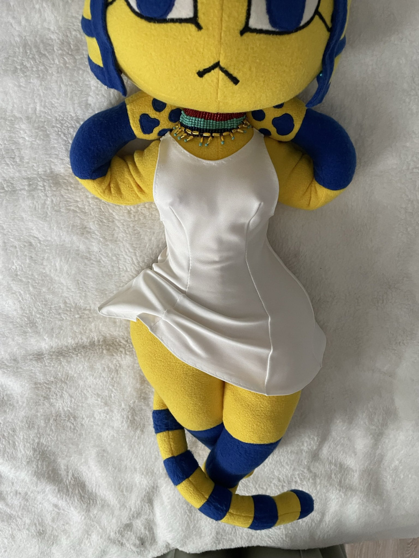 animal_crossing ankha_(animal_crossing) anthro bedding blanket blue_eyes clothed clothing dress felid feline female fur hi_res jewelry mammal markings nintendo nipple_outline plushie pussy_plush real solo solo_focus striped_markings striped_tail stripes tail tail_markings white_clothing white_dress yellow_body yellow_fur