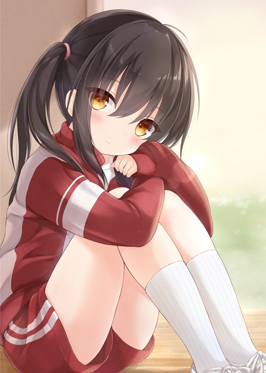 1girl black_hair blurry blurry_background blush closed_mouth commentary_request depth_of_field feet_out_of_frame gym_uniform hair_between_eyes highres hugging_own_legs jacket kneehighs knees_up light_smile long_hair looking_at_viewer mochizuki_riku original red_jacket red_shorts shirt shoes short_shorts shorts sidelocks sitting sleeves_past_wrists socks solo thighs track_jacket track_suit white_shirt white_socks yellow_eyes