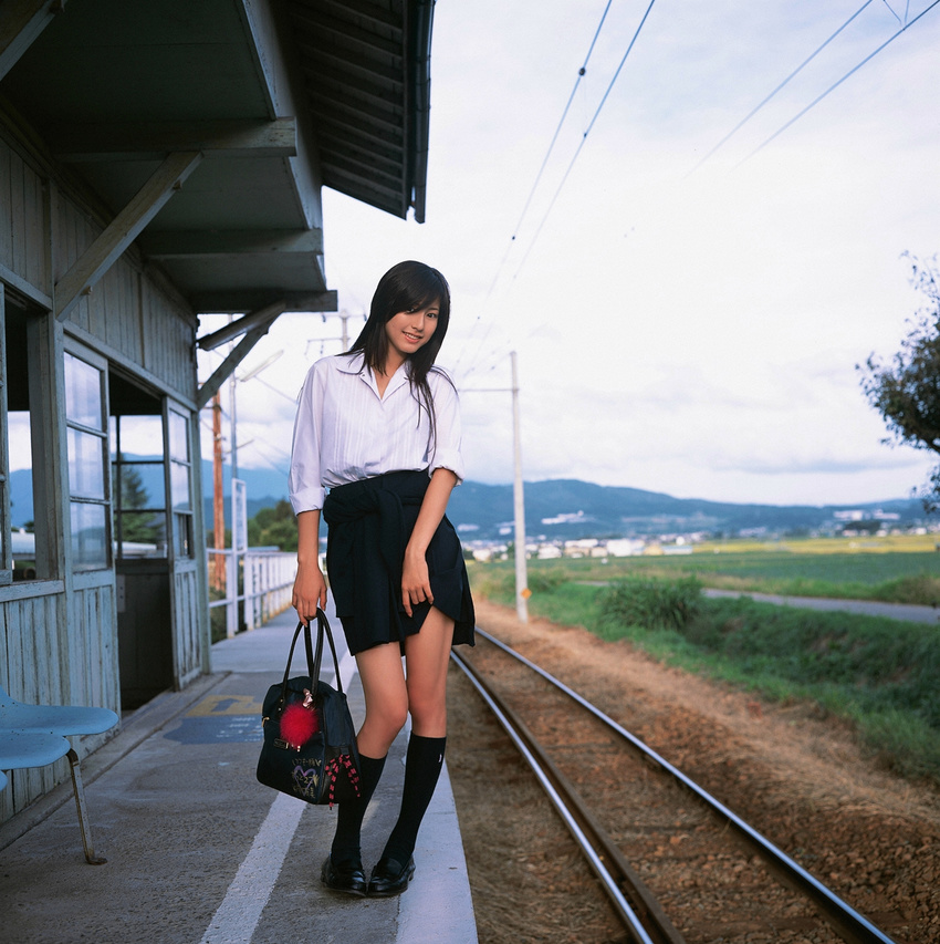 1girl asian brown_hair cosplay highres knee_socks kneehighs long_hair looking_at_viewer miniskirt photo pleated_skirt railroad_tracks school_bag school_uniform serafuku skirt skirt_lift socks solo standing sugimoto_yumi train_station