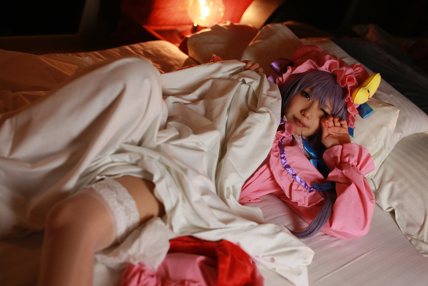 1girl asian bed blanket cosplay crescent dress female hat long_hair patchouli_knowledge photo pillow purple_hair solo tenshi_myu touhou