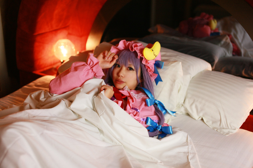 1girl asian bed blanket cosplay crescent dress female hat long_hair patchouli_knowledge photo pillow purple_hair solo tenshi_myu touhou