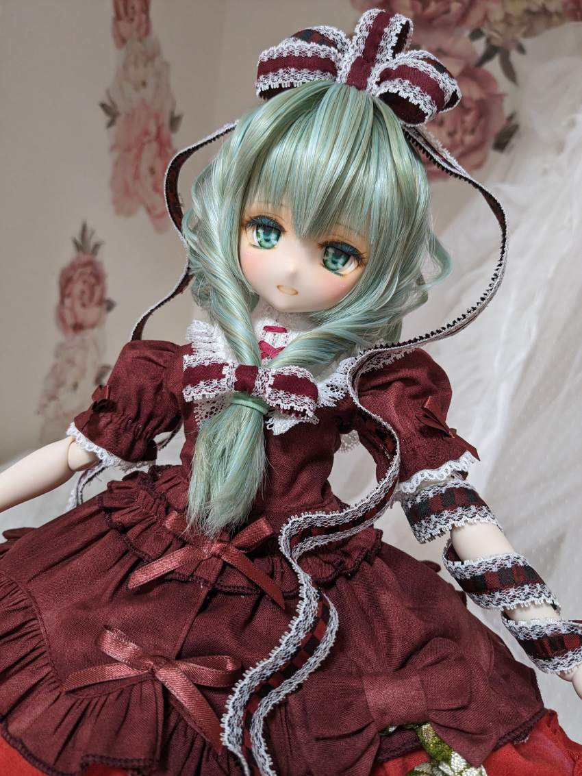 1girl adapted_costume arm_ribbon character_doll doll_joints dress frilled_dress frills front_ponytail green_eyes green_hair hair_ribbon highres joints kagiyama_hina lace-trimmed_dress lace-trimmed_ribbon lace_trim long_hair looking_at_viewer miyako_sasara photo_(medium) puffy_short_sleeves puffy_sleeves red_dress red_ribbon ribbon short_sleeves solo touhou upper_body