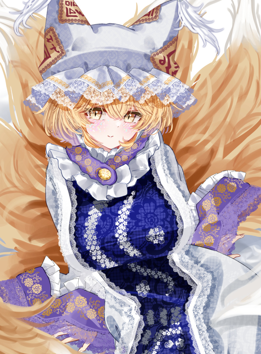 1girl animal_ears animal_hat blonde_hair blue_tabard breasts closed_mouth fox_ears fox_tail frilled_headwear hair_between_eyes hat highres kitsune kyuubi large_breasts looking_at_viewer mob_cap multiple_tails sarasadou_dan short_hair sitting smile solo tabard tail touhou yakumo_ran yellow_eyes