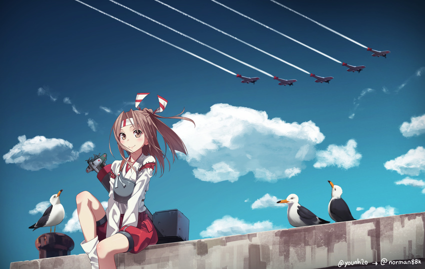 arrow bird blue_sky bollard brown_eyes brown_hair cloud condensation_trail d3a day flat_chest flight_deck hachimaki hair_ribbon harbor headband high_ponytail highres japanese_clothes kantai_collection light_brown_hair long_hair muneate ponytail quiver ribbon seagull shipyard shorts sitting sky yunamul zuihou_(kantai_collection)