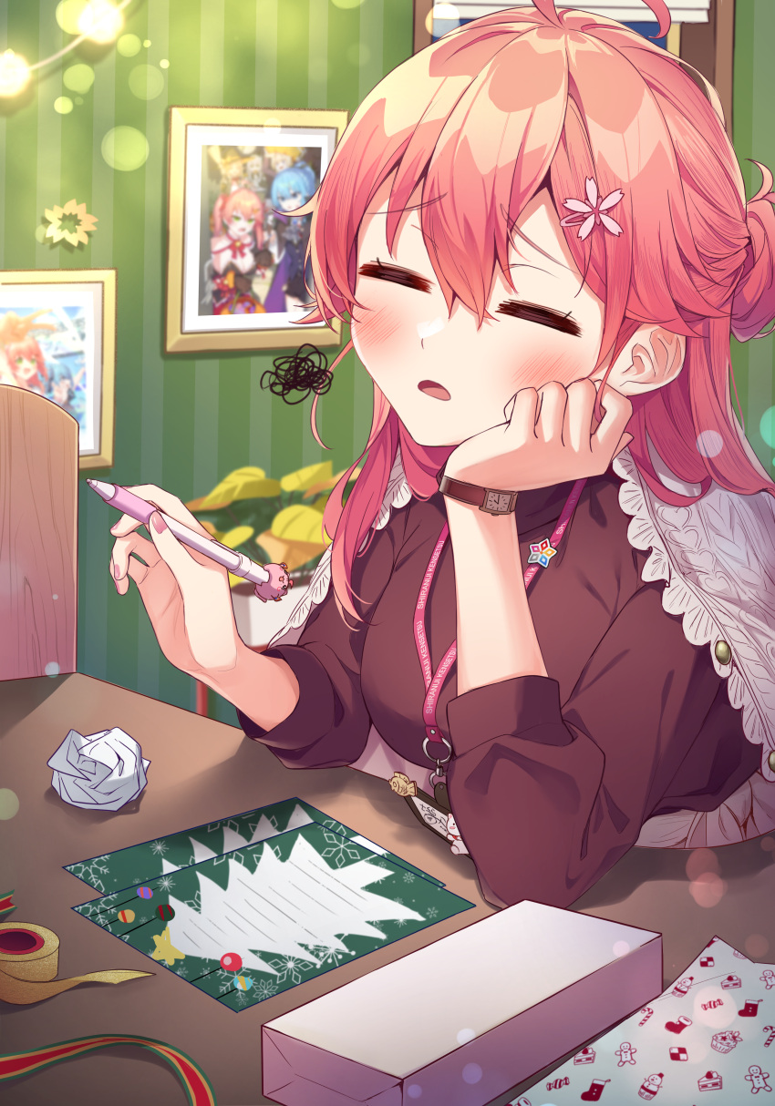 1girl =_= absurdres ahoge alternate_costume black_shirt blush christmas closed_eyes commentary crumpled_paper elbow_rest hair_between_eyes hands_up head_rest highres holding holding_pen hololive hoshimachi_suisei indoors lanyard long_hair long_sleeves open_mouth pen photo_(object) pink_hair sakura_miko scribble shirt solo table tang-du upper_body virtual_youtuber watch wrapping_paper wristwatch