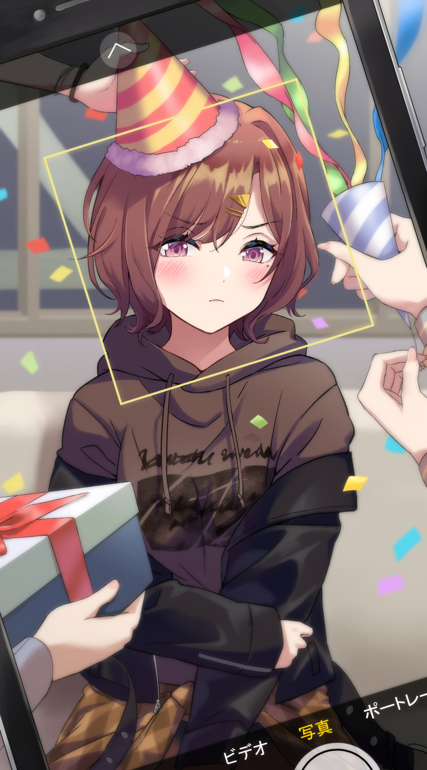 1girl absurdres black_jacket blush brown_hair brown_hoodie cellphone_photo closed_mouth confetti fingernails gift hair_ornament hairclip hat highres higuchi_madoka holding holding_gift holding_party_popper hood hood_down hoodie idolmaster idolmaster_shiny_colors jacket long_sleeves looking_at_viewer mole mole_under_eye off_shoulder open_clothes open_jacket out_of_frame party_hat party_popper purple_hair short_hair taking_picture v-shaped_eyebrows yeogpu_(seung832222)