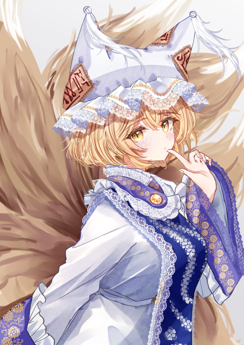 1girl animal_hat blonde_hair blue_tabard blush breasts dress finger_to_mouth fox_tail hat highres kitsune kyuubi lace-trimmed_headwear lace_trim large_breasts looking_at_viewer mob_cap multiple_tails sarasadou_dan slit_pupils solo tabard tail touhou white_dress yakumo_ran yellow_eyes