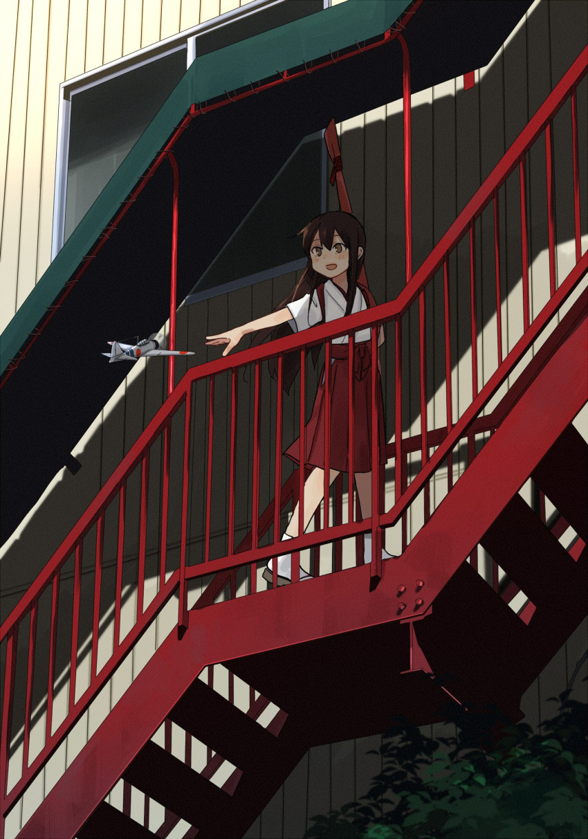 a6m_zero aircraft airplane akagi_(kantai_collection) annin_musou bow_(weapon) brown_hair commentary hakama hakama_skirt highres japanese_clothes kantai_collection kimono long_hair open_mouth outstretched_arm pleated_skirt red_hakama red_skirt short_sleeves skirt stairs tasuki weapon white_legwear younger
