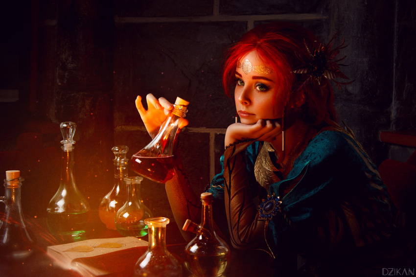 1girl book chin_rest circlet cosplay costume dress flask freckles helly_von_valentine_(disharmonica) indoors jewelry looking_afar makeup necklace pendant photo red_hair robe side_braids sitting solo table the_witcher triss_merigold upper_body