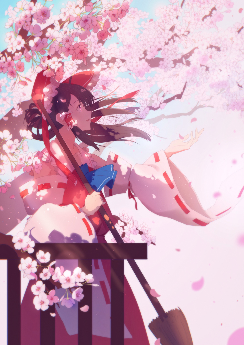 1girl arm_up blue_neckwear blue_sky bow broom brown_hair cherry_blossoms cowboy_shot cravat dappled_sunlight day detached_sleeves from_side hair_blowing hair_bow hair_tubes hakurei_reimu highres holding holding_broom hua_ben_wuming long_hair looking_up open_hand open_mouth outdoors parted_lips petals ponytail profile red_eyes red_skirt red_vest ribbon-trimmed_sleeves ribbon_trim sideways_mouth skirt sky solo standing sunlight touhou tree_branch vest wind