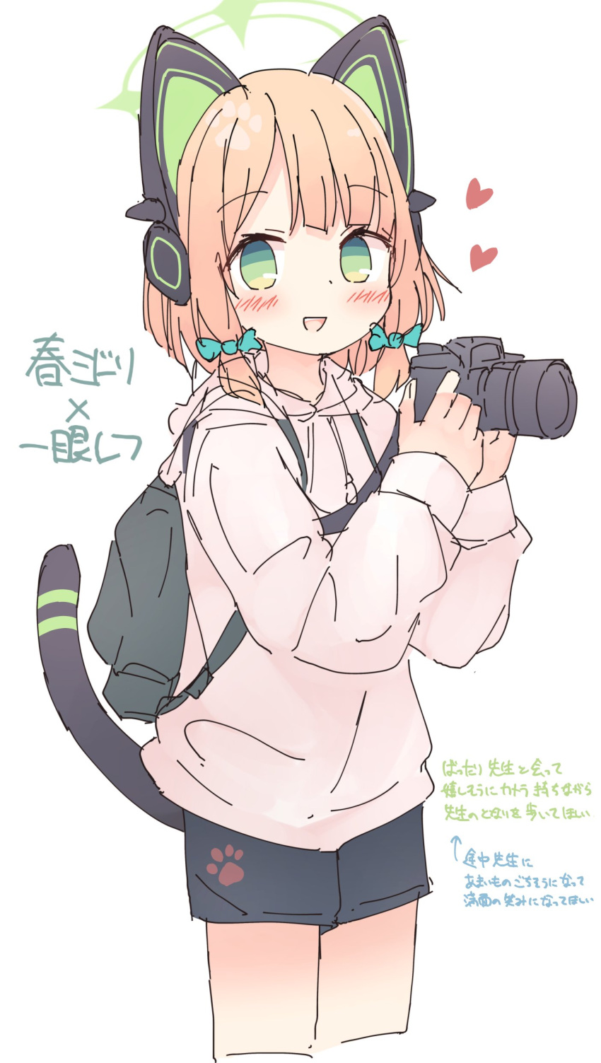 1girl absurdres animal_ear_headphones animal_ears backpack bag black_shorts blonde_hair blue_archive blush bow camera cat_tail cowboy_shot fake_animal_ears green_bow green_eyes green_halo hair_bow halo headphones heart highres holding holding_camera hood hood_down hoodie kamotsu_yasai long_sleeves looking_at_viewer midori_(blue_archive) open_mouth pink_hoodie short_hair shorts simple_background smile solo tail translation_request white_background