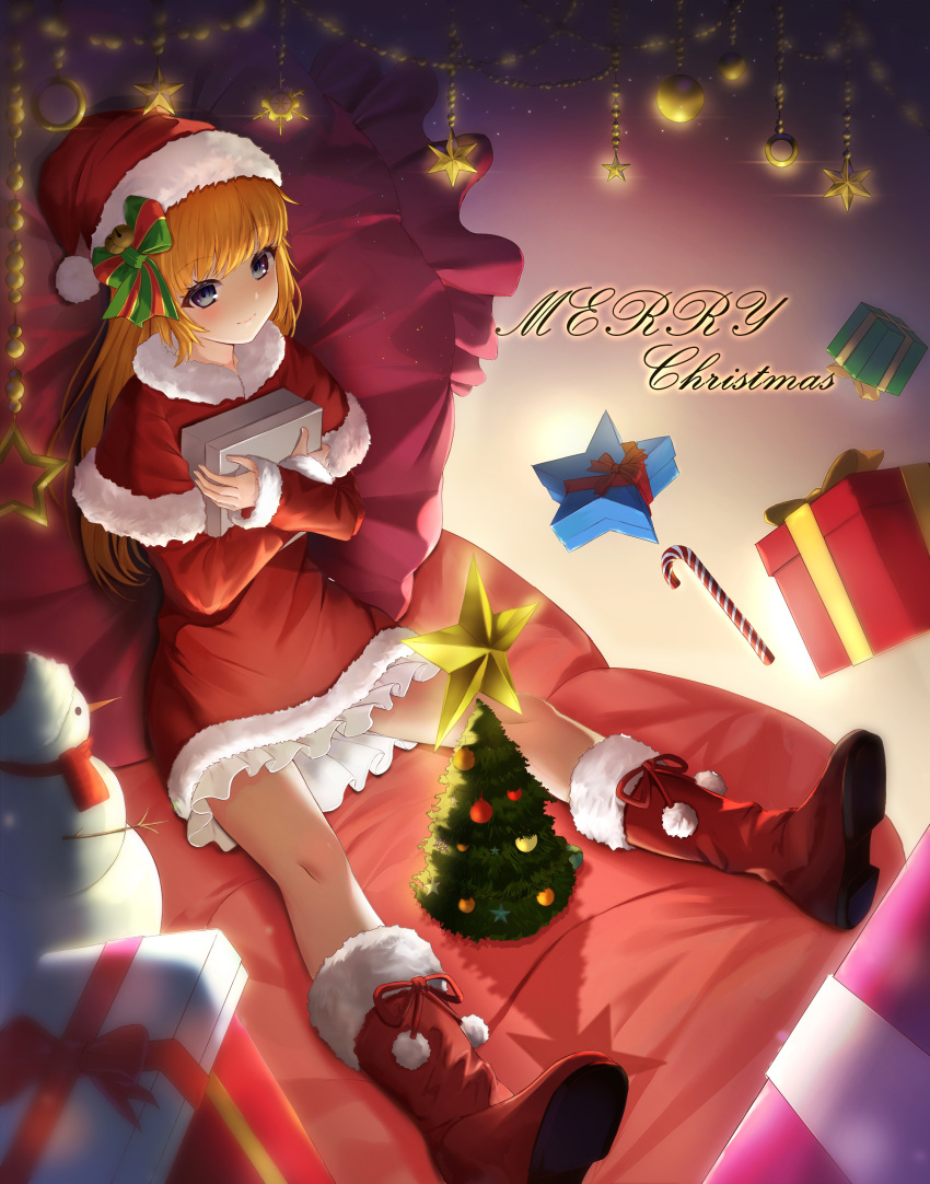 1girl absurdres bangs blanket blonde_hair blue_eyes boots candy candy_cane capelet christmas christmas_ornaments christmas_tree closed_mouth commentary cursive dress english_commentary food frilled_dress frills fur-trimmed_capelet fur_trim gift haires hat highres holding holding_gift long_hair long_sleeves looking_at_viewer merry_christmas original pillow red_capelet red_dress red_footwear santa_boots santa_costume santa_dress santa_hat short_dress sitting smile snowman solo star_ornament