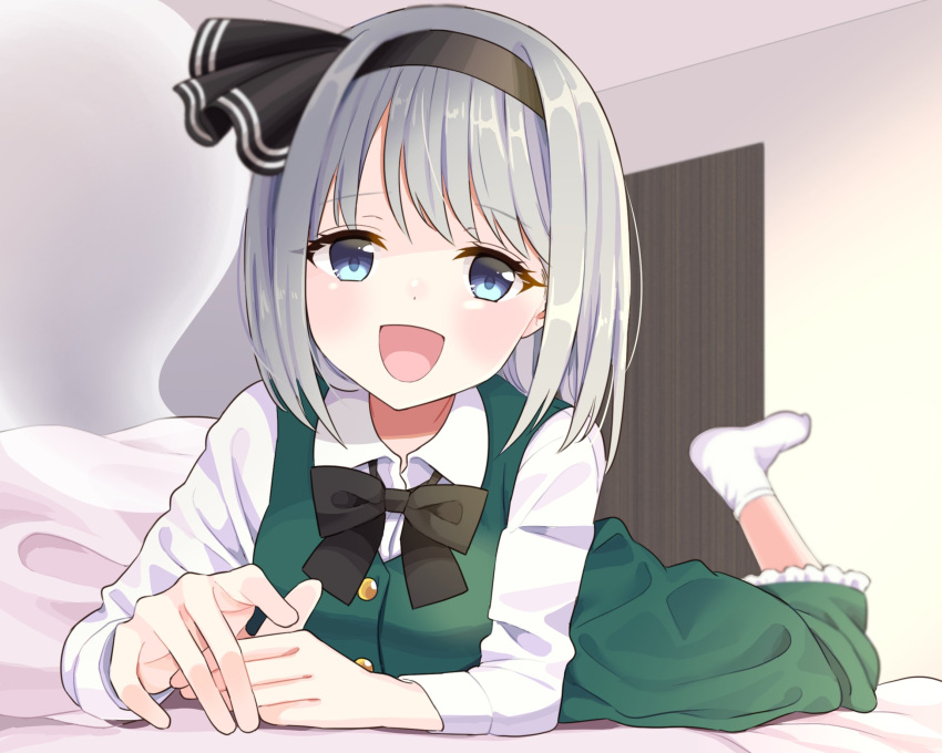1girl :d bangs bed_sheet black_bow black_bowtie black_hairband blush bob_cut bow bowtie breasts buttons collared_shirt commentary_request dot_nose eyebrows_visible_through_hair eyelashes ghost green_eyes green_skirt green_vest hairband happy highres hitodama konpaku_youmu konpaku_youmu_(ghost) long_sleeves looking_at_viewer lying medium_breasts on_bed on_stomach open_mouth pillow shirt short_hair silver_hair skirt smile socks solo stigma1101 touhou vest white_legwear white_shirt wing_collar