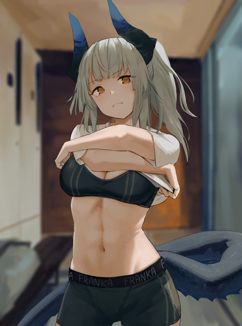 1girl arknights black_shorts black_sports_bra blurry blurry_background closed_mouth clothes_lift commentary contrapposto cowboy_shot dragon_horns dragon_tail english_text eyebrows_visible_through_hair highres horns indoors lifted_by_self linea_alba liskarm_(arknights) long_hair looking_at_viewer midriff navel noccu orange_eyes ponytail shirt shirt_lift shorts silver_hair solo sports_bra t-shirt tail undressing white_shirt