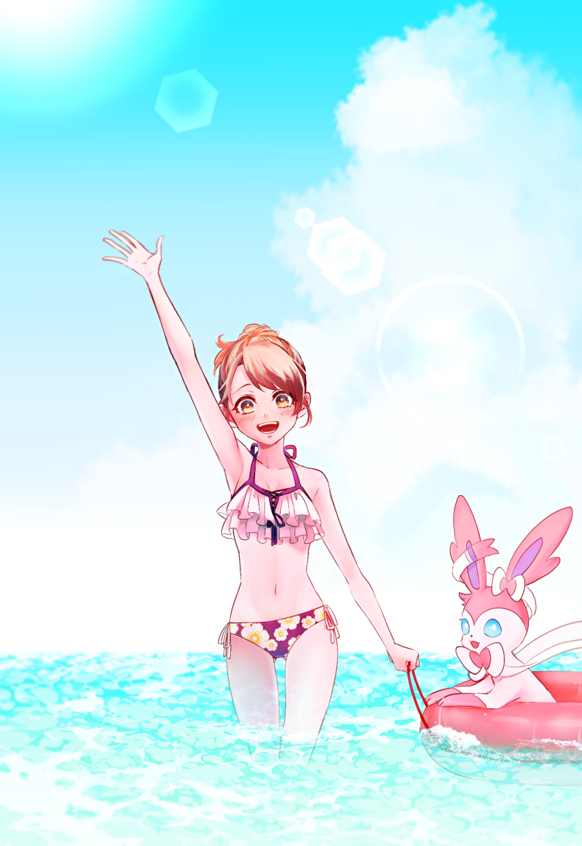 1girl :d arm_up ass_visible_through_thighs bangs bikini breasts brown_eyes brown_hair cleavage cloud collarbone day floral_print gen_6_pokemon gloria_(pokemon) halterneck highres innertube looking_at_viewer ocean open_mouth outdoors pokemon pokemon_(creature) pokemon_(game) pokemon_swsh print_bikini redrabbit44 ribbon short_hair side-tie_bikini small_breasts smile solo standing summer swept_bangs swimsuit sylveon thigh_gap waving white_ribbon