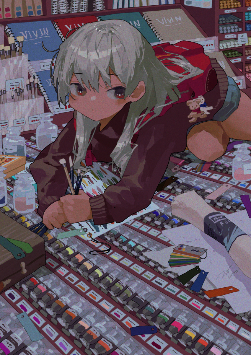 1girl all_fours backpack bag commentary_request denim denim_shorts drawing_equipment eyebrows_visible_through_hair grey_hair highres holding holding_paintbrush long_hair long_sleeves looking_at_viewer notebook original paint paint_tube paintbrush potg_(piotegu) red_eyes red_sweater shorts solo sweater