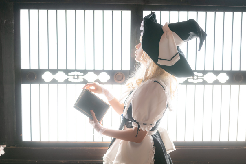 1girl absurdres apron back_bow backlighting black_headwear black_ribbon black_skirt black_vest blonde_hair book bow center_frills cosplay_photo cowboy_shot frills from_side hat hat_ribbon highres holding holding_book indoors kirisame_marisa large_bow medium_hair photo_(medium) puffy_short_sleeves puffy_sleeves ribbon ribbon-trimmed_sleeves ribbon_trim sakura1017 shirt short_sleeves skirt sleeve_ribbon solo touhou vest waist_apron white_apron white_bow white_ribbon white_shirt witch_hat