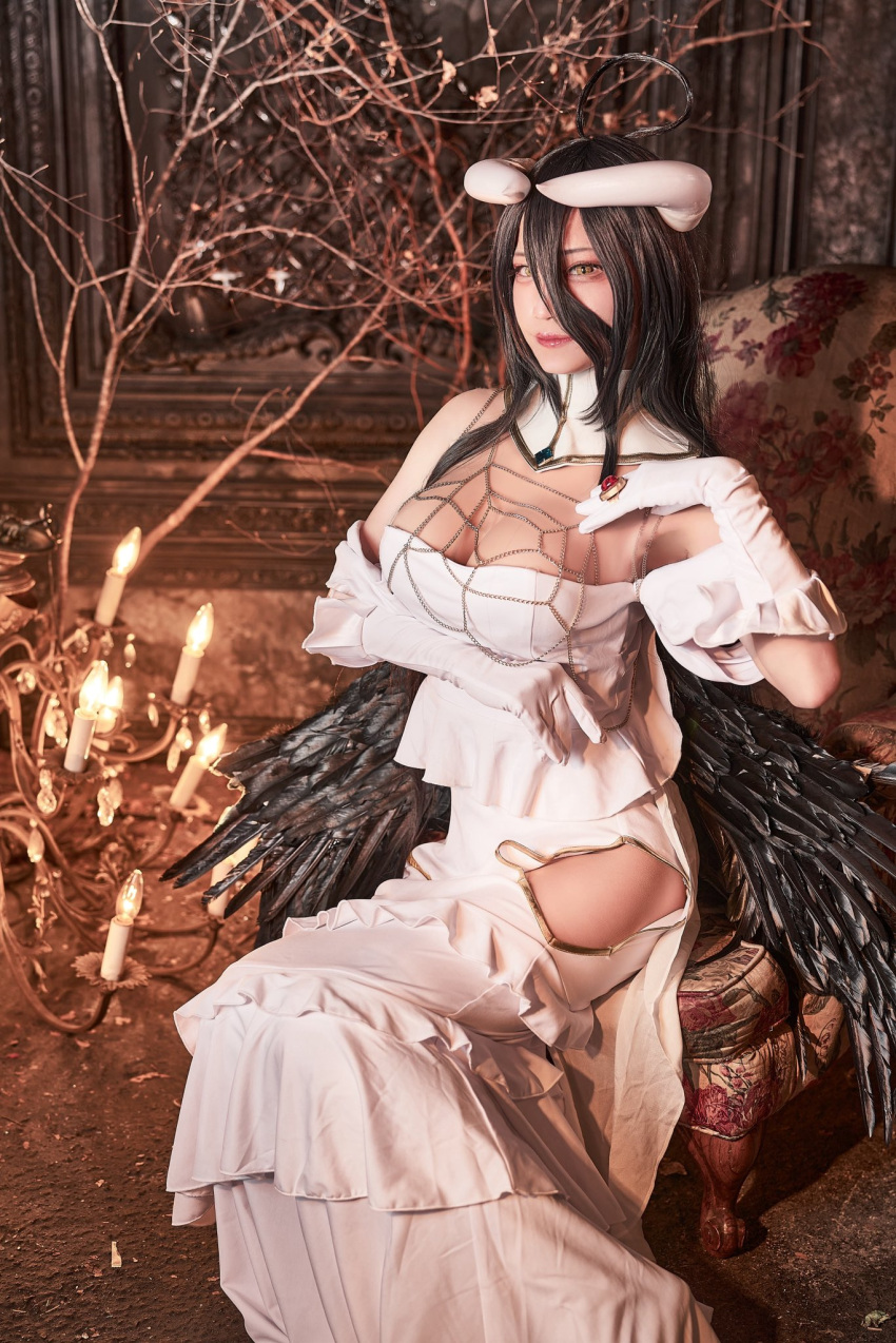 1girl albedo_(overlord) breasts brown_eyes chandelier cleavage cosplay_photo detached_collar dress gloves hand_on_own_chest highres hip_vent horns looking_at_viewer low_wings masyocos medium_breasts off-shoulder_dress off_shoulder overlord_(maruyama) photo_(medium) sitting smile solo white_dress white_gloves wings