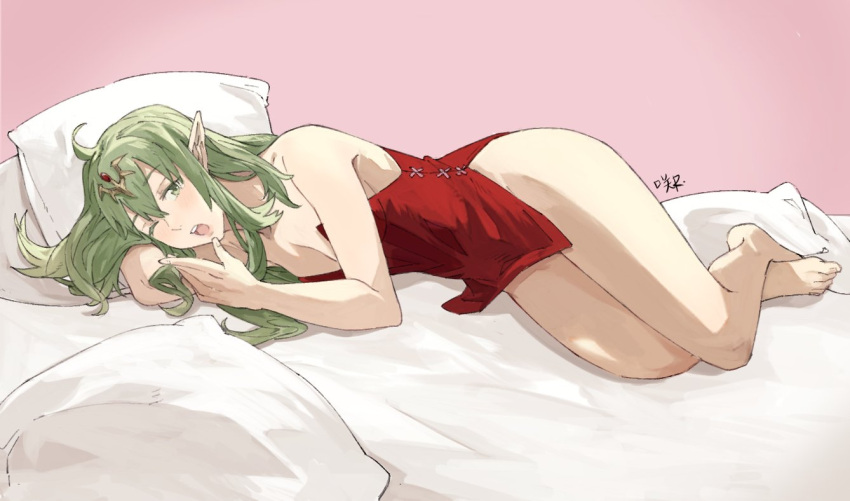1girl alternate_hairstyle bangs commentary dress english_commentary eyebrows_visible_through_hair fire_emblem fire_emblem_awakening fire_emblem_heroes green_eyes green_hair hair_between_eyes jewelry long_hair looking_at_viewer lying on_bed one_eye_closed open_mouth pillow pointy_ears red_dress sakuremi short_dress signature sleeveless sleeveless_dress solo strapless strapless_dress teeth thighs tiki_(dragon's_crown) tongue upper_teeth yawning