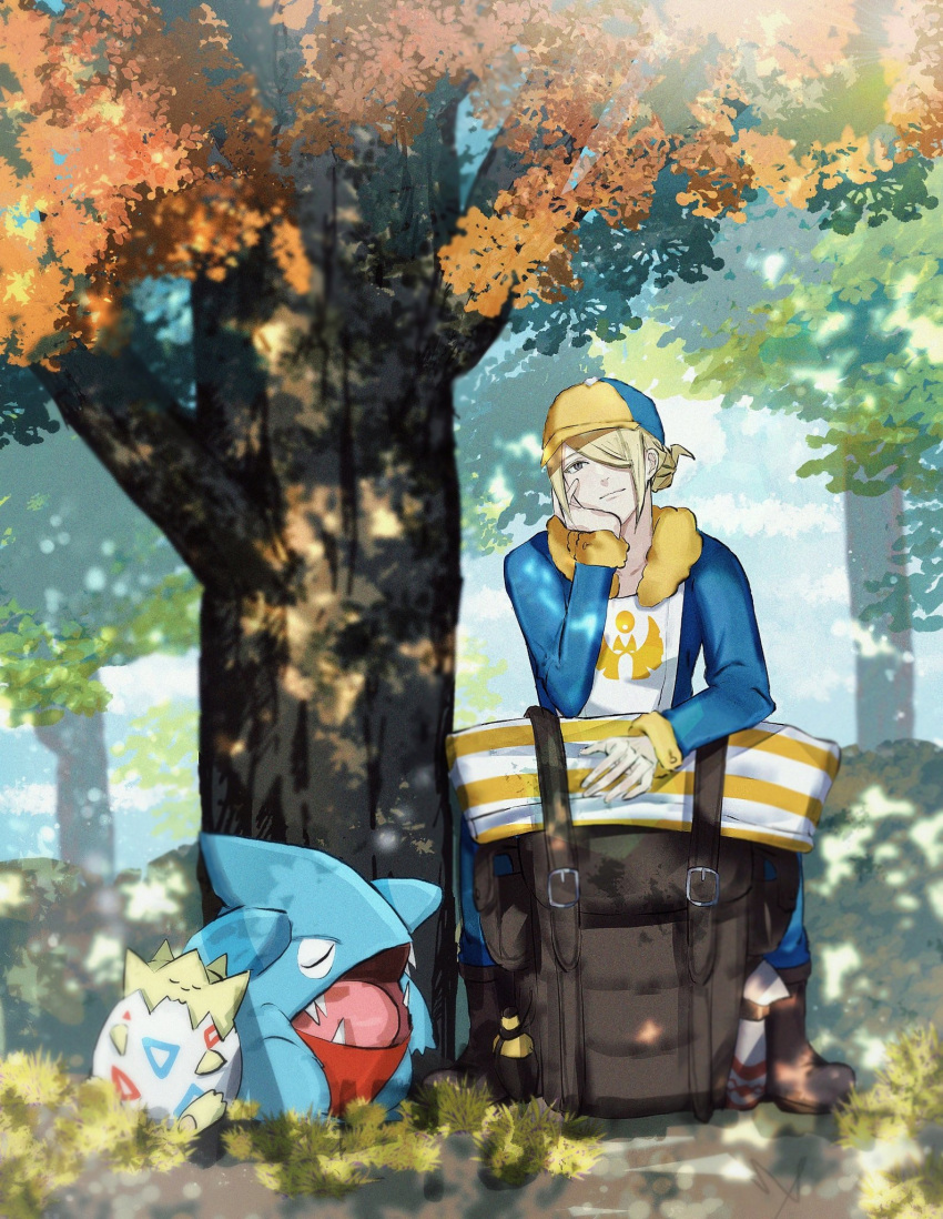 1boy backpack bag bag_removed bangs blonde_hair boots brown_bag brown_footwear closed_mouth collarbone commentary_request day fur_trim gible grass grey_eyes hair_over_one_eye hat head_rest head_tilt highres long_sleeves male_focus mr_(mst_011) outdoors pokemon pokemon_(creature) pokemon_(game) pokemon_legends:_arceus shadow short_hair sleeping togepi tree volo_(pokemon) yellow_headwear