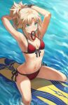  1girl armpits arms_behind_head arms_up bangs bare_shoulders bikini blonde_hair bracelet braid breasts collarbone fate/grand_order fate_(series) french_braid green_eyes highres jewelry long_hair looking_at_viewer mordred_(fate) mordred_(swimsuit_rider)_(fate) mordred_(swimsuit_rider)_(first_ascension)_(fate) mouth_hold navel ocean parted_bangs ponytail prydwen_(fate) red_bikini revision sidelocks small_breasts smile solo surfboard swimsuit thighs tonee tying_hair wet 