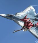  1girl 1other absurdres afu_(amzs8345) aircraft airplane asymmetrical_gloves black_shorts blue_sky camouflage canopy_(aircraft) chinese_commentary commentary_request day elbow_gloves fighter_jet flight_suit flying full_body gloves hat helmet highres jacket legs looking_to_the_side magical_girl medium_hair military military_vehicle original outdoors pilot pilot_helmet red_hair red_hat red_jacket red_star roundel russian_air_force shoes shorts sky staff staff_riding star_(symbol) stuffed_animal stuffed_toy su-57 thighs white_shoes witch_hat 