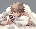  1boy bakugou_katsuki bare_arms bare_shoulders blanket blonde_hair boku_no_hero_academia commentary_request grey_background highres holding holding_phone lying male_focus on_stomach open_mouth phone pillow red_eyes sesami_dkt short_hair simple_background solo spiked_hair under_covers 