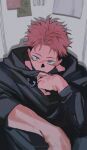  1boy black_hoodie black_pants brown_eyes covering_mouth facial_mark highres hood hood_down hoodie indoors itadori_yuuji jujutsu_kaisen k00s long_sleeves looking_at_viewer male_focus pants paper pink_hair scar scar_on_face short_hair sitting solo undercut veins 