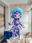  1girl absurdres ai_chi_jianguo_xiaosong_xu animification apex_legends artist&#039;s_hand_in_frame blue_bodysuit blue_eyes blue_hair blurry blurry_background bodysuit chinese_commentary clay_(medium) gloves goggles highres holding holding_pen horizon_(apex_legends) looking_at_viewer multicolored_bodysuit multicolored_clothes official_alternate_costume open_mouth overfloater_horizon pen photo_(medium) purple_bodysuit short_hair smile solo unconventional_media white_gloves 