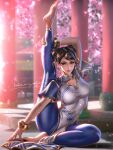 1girl arm_support barefoot blue_pants blurry blurry_background bracelet cherry_blossoms chest_cutout chinese_clothes chun-li double_bun flexible hair_bun hair_ribbon highres jewelry leg_hold leg_lift leg_up liang_xing looking_at_viewer pants petals ribbon solo split street_fighter street_fighter_6 stretching 