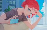  1girl arm_up belt blue_eyes cellphone cloud curtains highres holding holding_phone indoors kisei2 looking_at_viewer lying on_stomach open_mouth original phone plant purple_shirt red_hair shirt short_hair short_sleeves smartphone solo t-shirt 