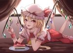  1girl :d ascot barefoot blonde_hair cake cake_slice crystal curtains erisauria flandre_scarlet food full_body hat hat_ribbon highres indoors legs_up looking_at_viewer lying mob_cap on_stomach one_side_up open_mouth plate red_eyes red_ribbon ribbon short_sleeves smile solo touhou white_headwear window wings wrist_cuffs yellow_ascot 