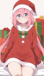  1girl blue_eyes blush bow bowtie box closed_mouth commentary dress fur-trimmed_dress fur-trimmed_headwear fur_trim gift gift_box green_bow green_bowtie hair_between_eyes hat highres kagamihara_nadeshiko long_hair long_sleeves looking_at_viewer nekosination pink_hair red_dress red_hat sailor_collar santa_costume santa_hat sidelocks sitting smile solo twitter_username white_sailor_collar yurucamp 