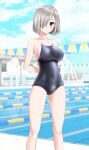  1girl absurdres alternate_costume arms_behind_back black_one-piece_swimsuit blue_eyes blue_sky breasts cloud commentary_request competition_school_swimsuit day feet_out_of_frame grey_hair hair_ornament hair_over_one_eye hairclip hamakaze_(kancolle) highres kantai_collection lane_line large_breasts looking_at_viewer outdoors parted_lips pool school_swimsuit short_hair sky solo string_of_flags swimsuit takafumi 