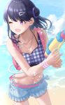  1girl absurdres backpack bag beach bikini bikini_shorts black_hair blue_sky cloud commentary_request day fangs fukumaru_koito hair_bun hair_down hair_ornament hairclip highres idolmaster idolmaster_shiny_colors looking_at_viewer looking_down navel ocean oka_yuto one_eye_closed outdoors purple_eyes shorts skin_fangs sky solo stomach swimsuit water water_gun 