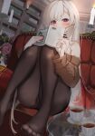  1girl azur_lane bangs bare_shoulders belfast_(azur_lane) blush book candle cup earrings flower highres holding holding_book jewelry knees_up long_hair looking_at_viewer marumai pantyhose purple_eyes red_nails sitting solo sweater tea teacup very_long_hair 