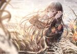  1girl bangs black_shirt blurry blurry_background blush brown_eyes brown_hair closed_mouth cloud grass hands_in_hair hands_up highres lace long_hair long_sleeves original outdoors sakura_(39ra) shirt sky solo standing sunset 