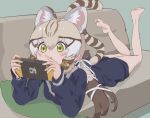  1girl animal_ears bare_legs barefoot blonde_hair blue_sweater blush bow brown_hair cat_ears cat_girl cat_tail commentary extra_ears geoffroy&#039;s_cat_(kemono_friends) green_eyes hair_bow kemono_friends kunikuni_(kunihiro2005) long_hair long_sleeves lying multicolored_hair nintendo_switch on_stomach sailor_collar school_uniform sidelocks solo sweater symbol-only_commentary tail the_pose twintails white_bow 