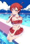  1girl absurdres angel_gabriel. bikini blue_eyes blush breasts cleavage cloud collarbone day embarrassed hair_bun heart heart_print highres looking_at_viewer love_live! love_live!_superstar!! medium_breasts navel outdoors pool red_bikini red_hair sitting solo swimsuit water wavy_mouth yoneme_mei 