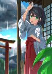  1girl absurdres arm_up bangs blue_sky closed_mouth cloud cloudy_sky commentary_request day green_eyes hair_between_eyes hair_ornament hair_tie hair_tie_in_mouth hairclip hakama hakama_skirt highres japanese_clothes kimono long_sleeves miko mouth_hold original outdoors rain red_hakama skirt sky solo torii tsuyukina_fuzuki water_drop white_kimono wide_sleeves x_hair_ornament 