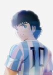  1boy argentina argentinian_flag_print black_eyes black_hair captain_tsubasa commentary_request curly_hair from_behind grin highres ishibashi_daisuke juan_diaz looking_at_viewer short_hair short_sleeves simple_background smile soccer_uniform solo sportswear upper_body white_background 