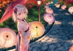  1girl autumn_leaves bangs blurry blurry_background blush bush closed_mouth feet_out_of_frame flower hair_flower hair_ornament hiten_(hitenkei) holding holding_umbrella japanese_clothes kimono looking_at_viewer medium_hair oil-paper_umbrella orange_eyes original outdoors pink_flower print_kimono shiny shiny_hair smile solo standing stone sunlight trail tree umbrella white_hair white_kimono 