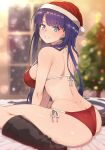  1girl ass bikini blue_eyes boots breasts christmas_ornaments christmas_tree earrings fate/grand_order fate_(series) grin hat highres indoors jewelry large_breasts long_hair martha_(fate) pononozo purple_hair red_bikini santa_hat sitting smile solo strap_gap swimsuit thighs wariza 