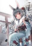  1girl animal animal_ear_fluff animal_ears arrow_(projectile) bangs bare_tree blue_kimono blurry blurry_foreground branch chinese_zodiac commentary depth_of_field ema feet_out_of_frame floral_print flower fur_collar grey_hair hair_flower hair_ornament hamaya holding holding_arrow japanese_clothes kimono long_hair long_sleeves midorikawa_you obi original outdoors print_kimono rabbit rabbit_ears red_eyes sash sitting snowing solo symbol-only_commentary torii tree twintails very_long_hair white_flower wide_sleeves year_of_the_rabbit 